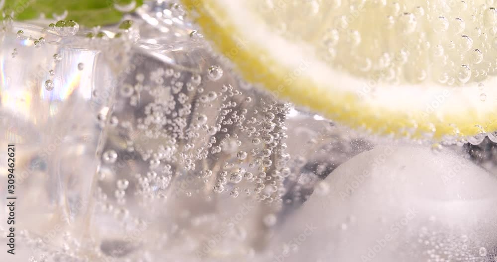 Soda water with ice and lemon, closeup. Slow motion effect Soda water with ice and lemon, closeup. Slow motion effect