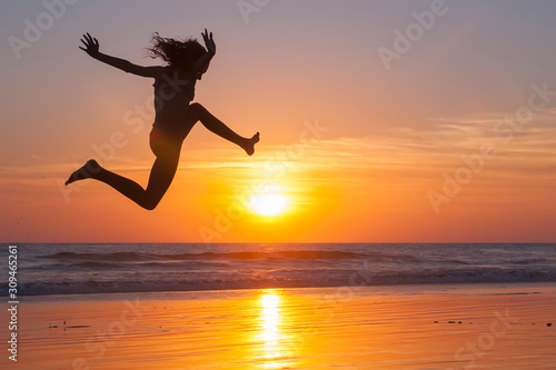 girl jumping on the beach at sunset