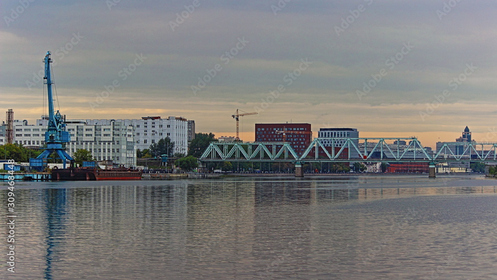 Bridge on Moscow River near Kozhukhovsky Zaton on Summer evening on Port crane and city buildings background, water industrial landscape