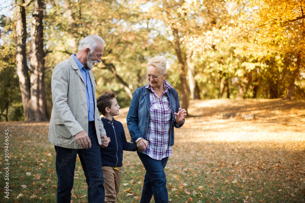 Grandparents and their grandson strolling through a park in an autumn afternoon. Grandparents and their grandson strolling through a park in an autumn afternoon.