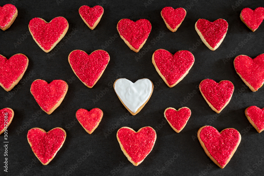 Red and white heart shaped cookies on black background, distinction concept, love symbol Red and white heart shaped cookies on black background, distinction concept, love symbol