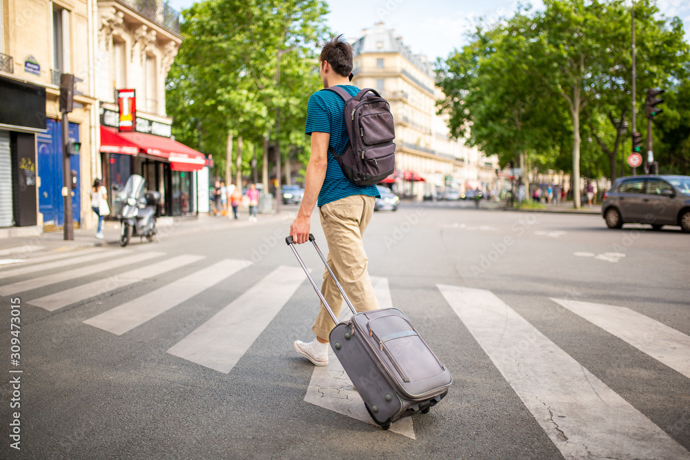 Full body behind of young travel man walking on city street with ...