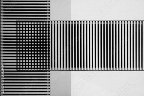 Lath structures viewed as regular stripes and checkers pattern in shades of gray. Business architecture background resembling bar codes against white stucco wall. Abstract geometric template.