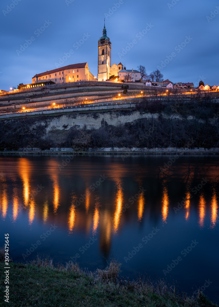 Scenic view of the historic old town Melnik in the Central Bohemia at twilight. Gothic cathedral and castle on top of hill with vineyards by the river