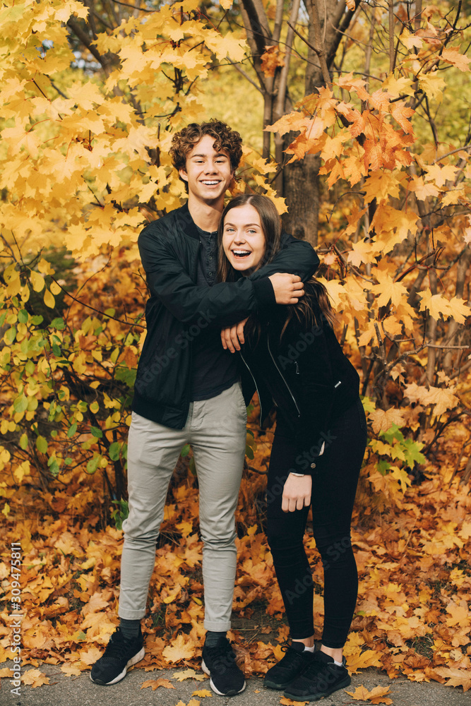 Full length of happy teenage friends smiling against trees in autumn Full length of happy teenage friends smiling against trees in autumn