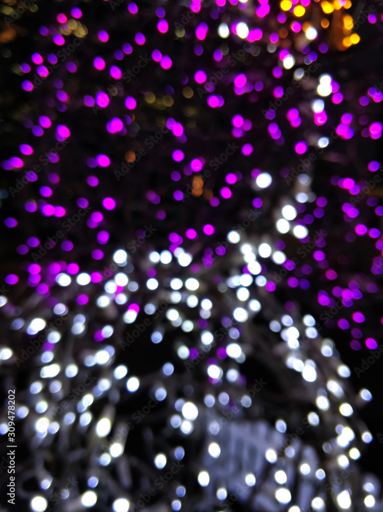 Blurred street lights in Night city. Glitter white and purple lights on black background. Christmas celebration and New Year. Modern pattern for design and backdrop