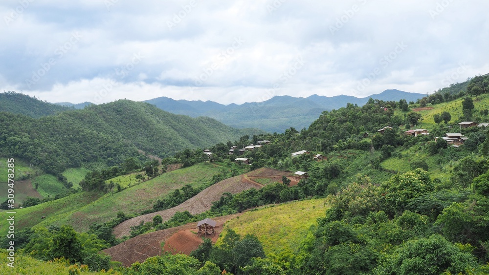 Beautiful village of ethnic group / hill tribe people in a valley of Northern Thailand with green forest, white clouds and blue sky. Beautiful village of ethnic group / hill tribe people in a valley of Northern Thailand with green forest, white clouds and blue sky.