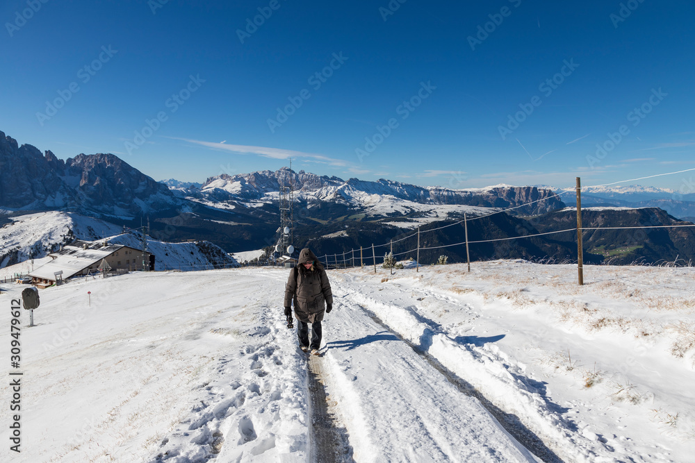 Female photographer in winter clothes on snowy mountains in Italian Dolomites - Seceda.