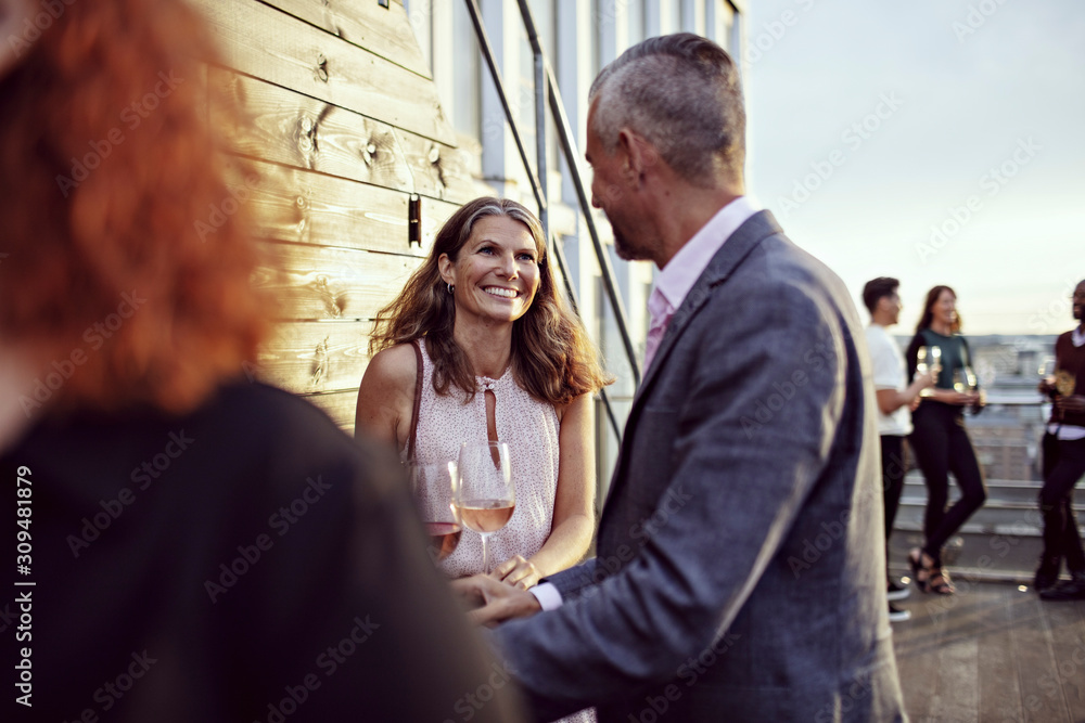 Smiling businesswoman talking with coworker in party on terrace Smiling businesswoman talking with coworker in party on terrace