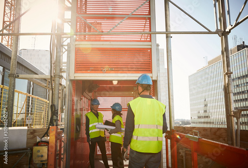 Male and female engineers at freight elevator in construction site