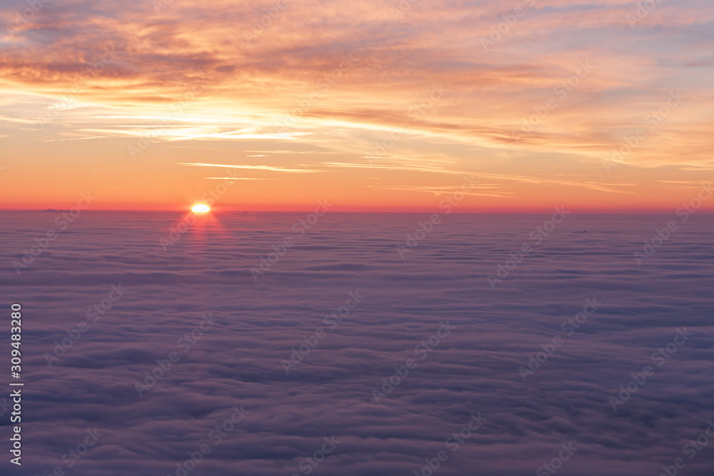 Wonderful view of snowy landscape covered with fog and clouds. The setting sun is staining the sky. Wonderful view of snowy landscape covered with fog and clouds. The setting sun is staining the sky.