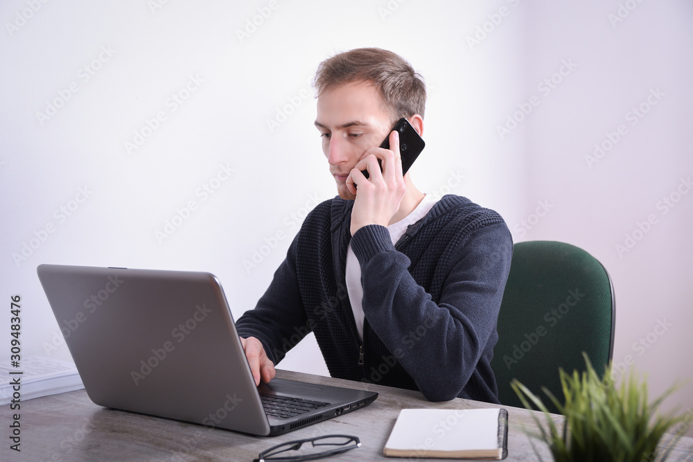 Portrait of young business man sitting at his desk desktop laptop technology in the office.Internet marketing, finance, business concept Portrait of young business man sitting at his desk desktop laptop technology in the office.Internet marketing, finance, business concept