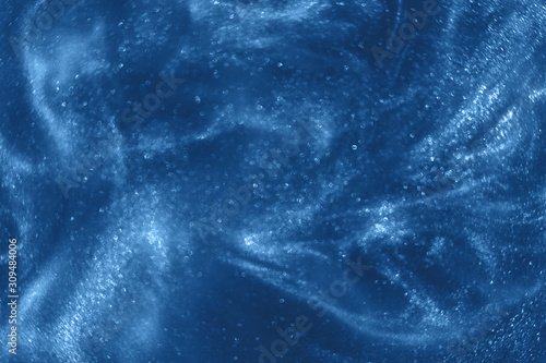 Abstract elegant, detailed classic blue glitter particles flow with shallow depth of field underwater. Holiday magic shimmering luxury background. Festive sparkles. Color of the year 2020 