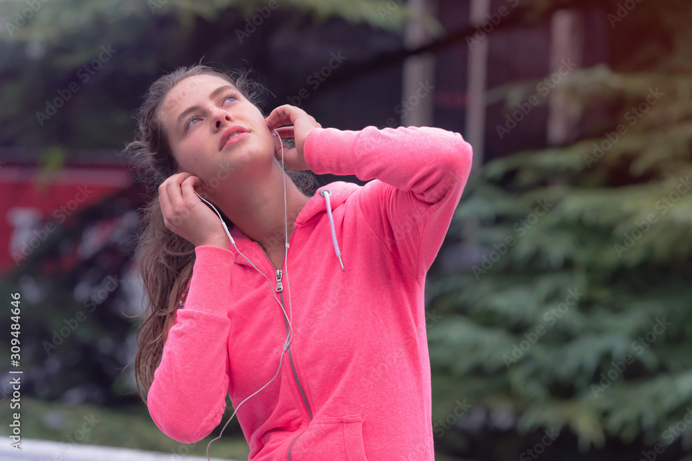 Healthy young female sporty woman prepairing for running in morning on street, using phone before running. Runner training outdoors in morning.