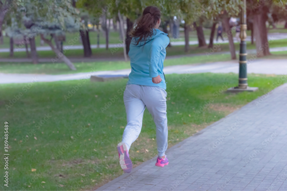 Fototapeta premium Young female woman running outdoors in urban road. Young female exercising in sport clothes.