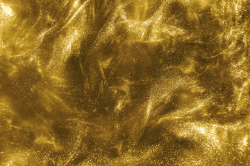 Abstract elegant, detailed gold glitter particles flow with shallow depth of field underwater. Holiday magic shimmering luxury background. Festive sparkles and lights. de-focused.