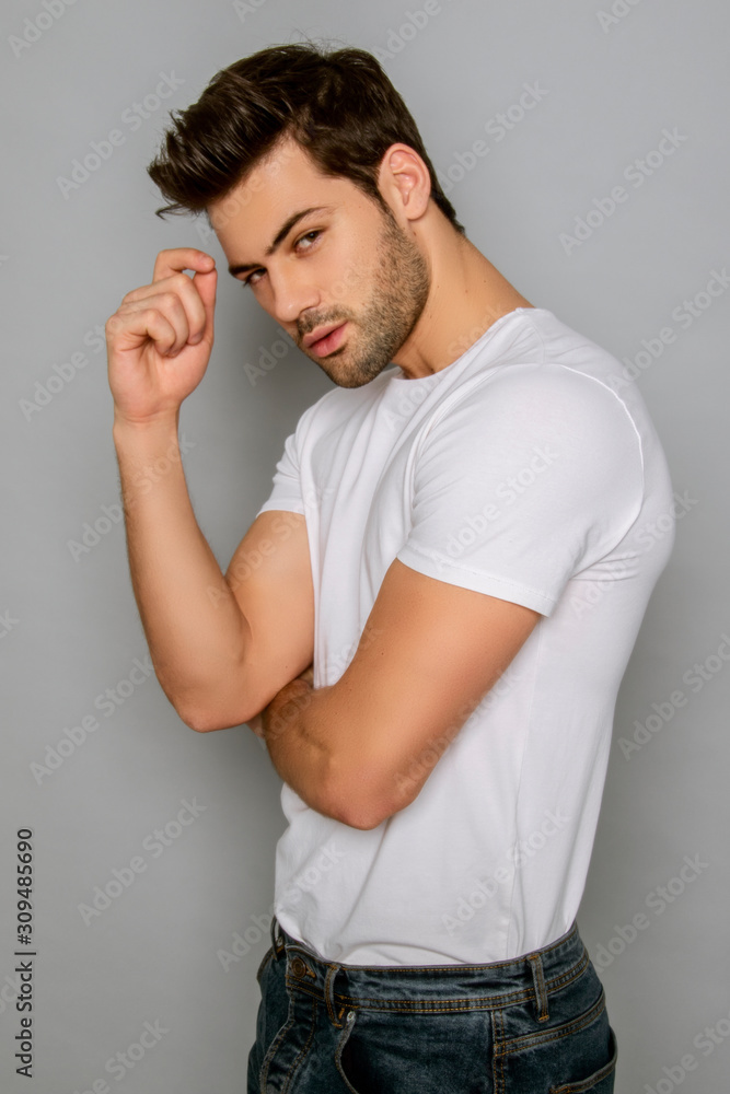 Muscle strong face beautiful stripped male model portrait in denim blue jeans white t-shirt on grey isolated font background with shadow Muscle strong face beautiful stripped male model portrait in denim blue jeans white t-shirt on grey isolated font background with shadow