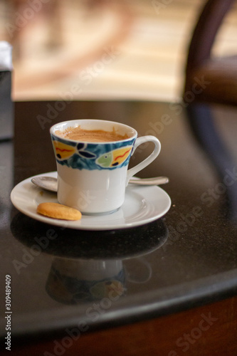 Coffee cup with biscuit on dark table.