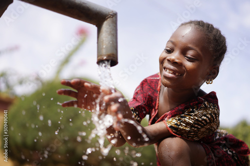 Water is Life for African Children, Little Gorgeous Black Girl Drinking from Tap photo