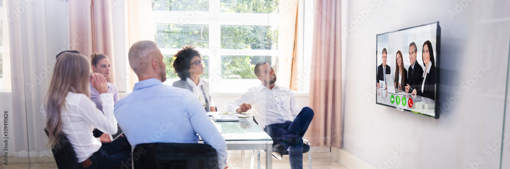 Group Of Diverse Businesspeople Video Conferencing In Boardroom Group Of Diverse Businesspeople Video Conferencing In Boardroom