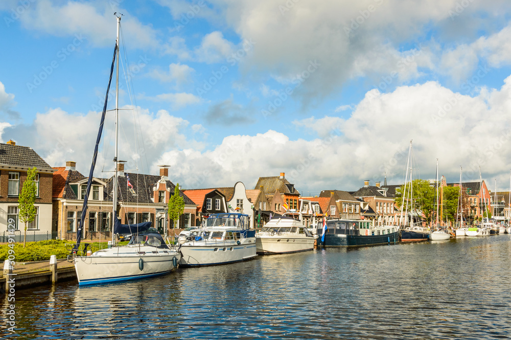 Dutch canal with moored boats on the shore, city of Lemmer.