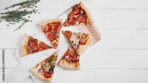 Banner 16 x 9 size image for web. Hot Italian pizza with melting tomato,pepperoni and cheese on a white rustic wooden table