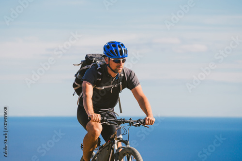 young guy riding a mountain bike on a bicycle route in Spain. Athlete on a mountain bike rides off-road against the background of the Mediterranean Sea, Costa Brava. Cycling in Spain