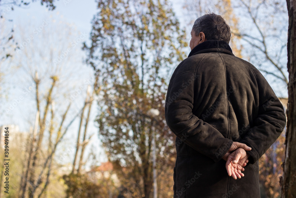 Senior man walking and relaxing in park. Walking away, relaxing, rear view Senior man walking and relaxing in park. Walking away, relaxing, rear view