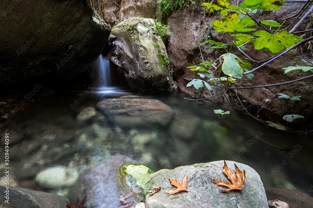 Obraz premium Idyllic calm lake with blue clean water and small waterfall flowing between the rocks.