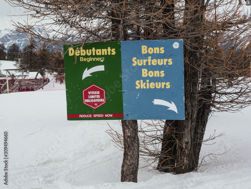 Signs at the edge of a ski slope. Beginners on the left, and good skiers on the right, in the Risoul ski resort, in France. photo