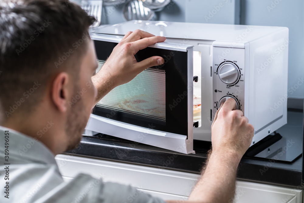 Man Preparing Food In Microwave Oven Man Preparing Food In Microwave Oven