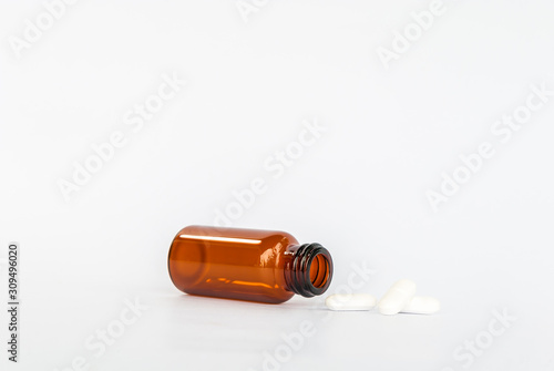 white pills spilling out brown glass supplement medicine isolated on white background 