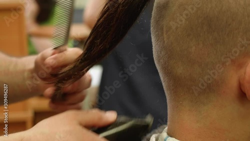 Barber wokrs with hairclipper on client's head. Close up view of yound man's head. Pony tail on man's head. Modern stylish haircut. photo