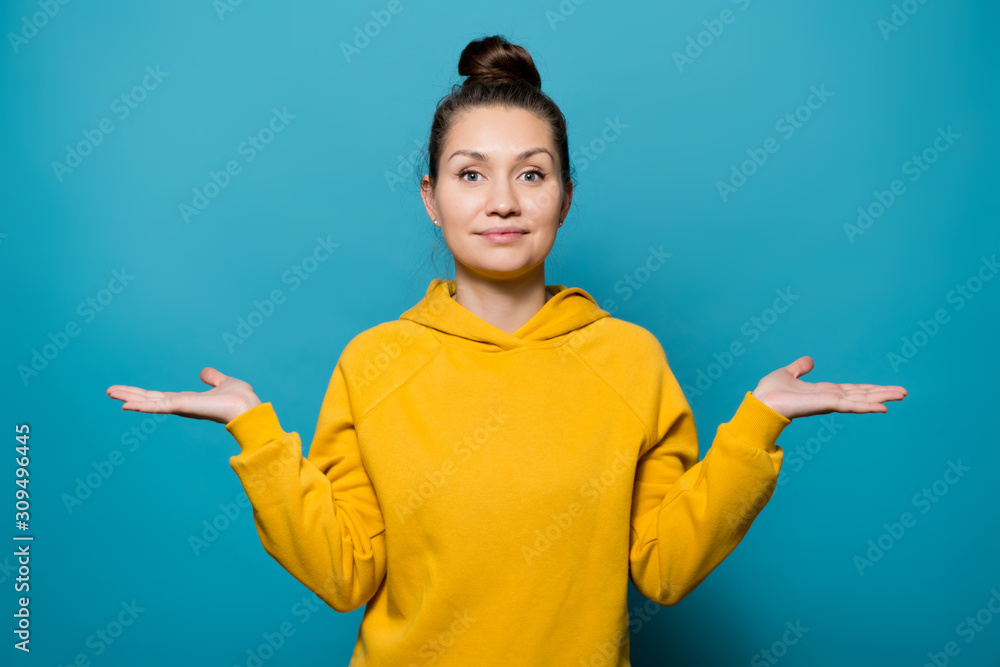 girl in a bright sweatshirt points her palms up, depicting a choice or scales girl in a bright sweatshirt points her palms up, depicting a choice or scales