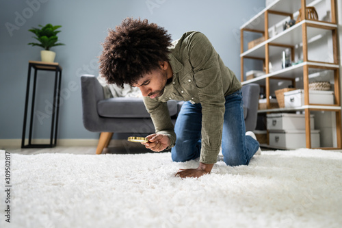 Male Looking At Carpet With Magnifying Glass