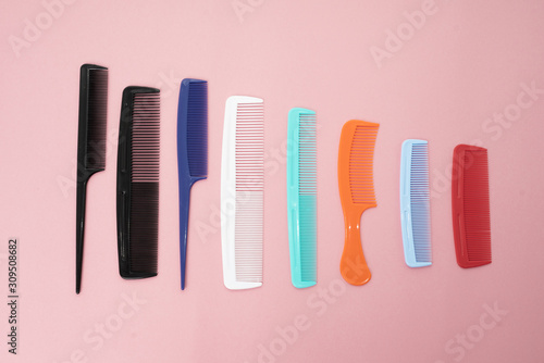 Various colored brushs and combs for hair on pink background. collection of combs