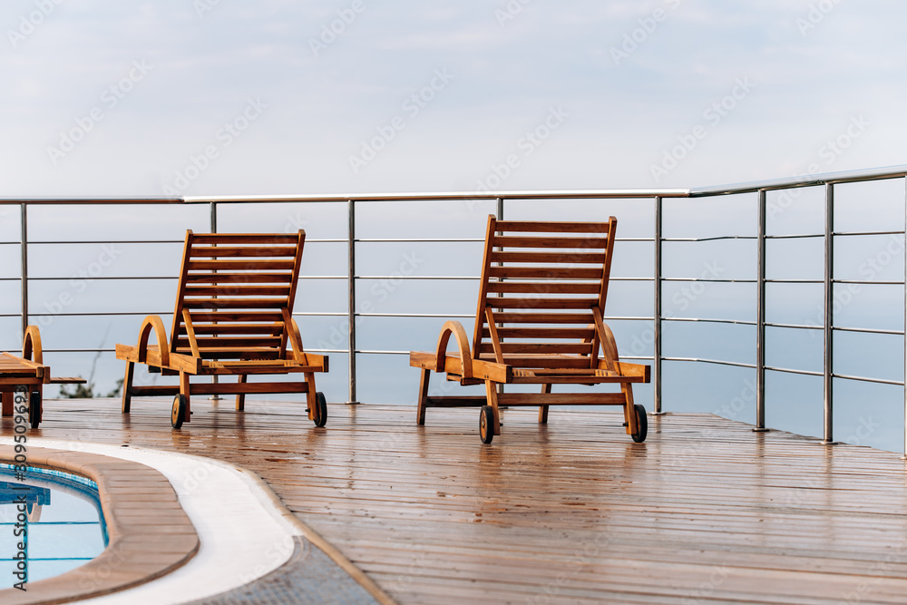 Wooden deck chairs in the hotel with scenic views of the ocean or sea Wooden deck chairs in the hotel with scenic views of the ocean or sea
