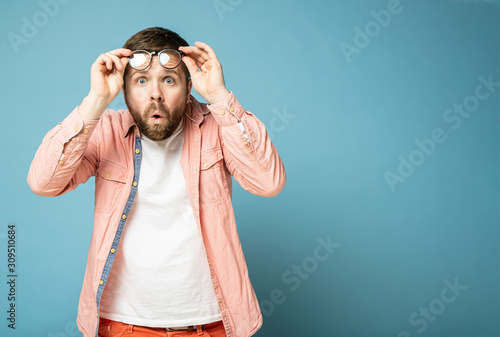 Foto Stunned man looks in surprise at the camera and opens mouth from shock, with copy space