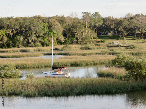 Sailboat docked in marsh area with trees and water in Georgia