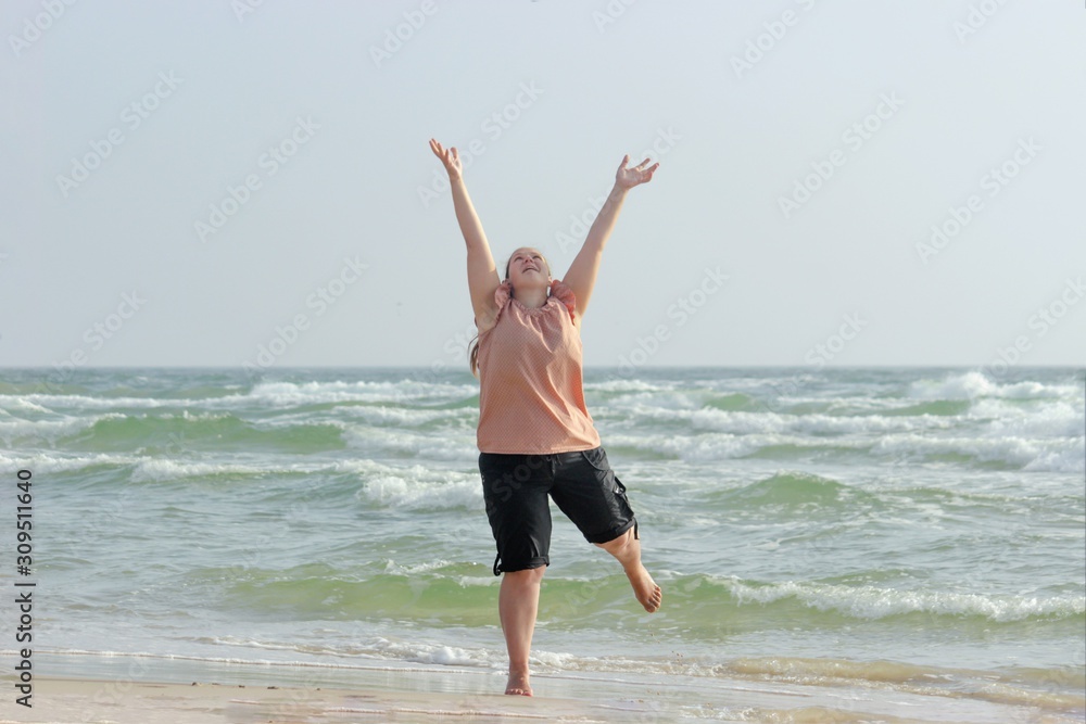 Contented girl is jumping on the beach against the background of the sea. Contented girl is jumping on the beach against the background of the sea.