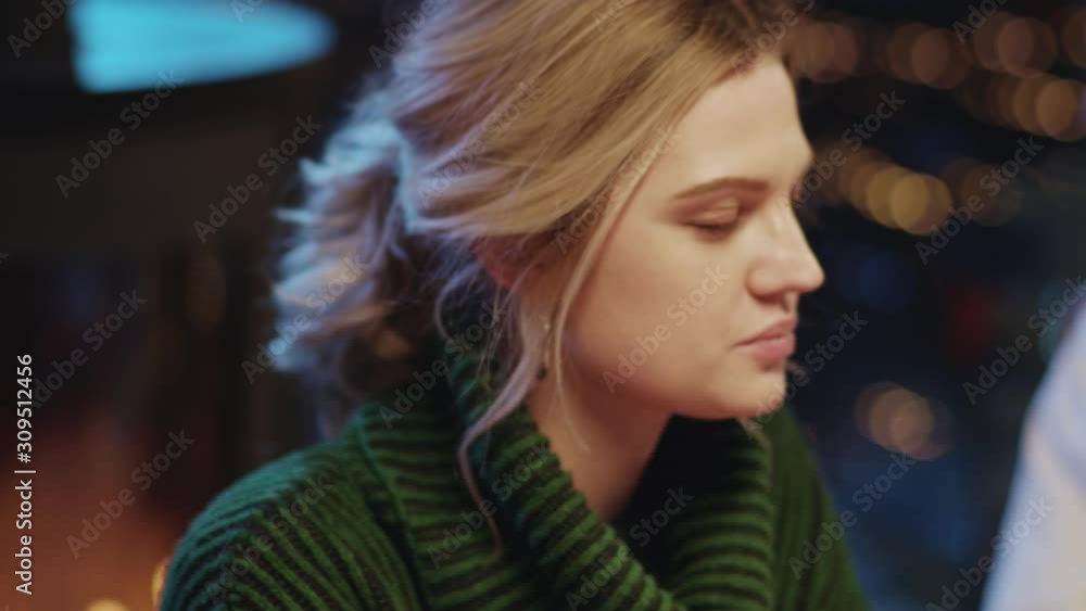 Pretty enchanting blonde girl drinking wine at dinner table talking in company of friends having great party holiday celebration at Christmas winter night. Pretty enchanting blonde girl drinking wine at dinner table talking in company of friends having great party holiday celebration at Christmas winter night.