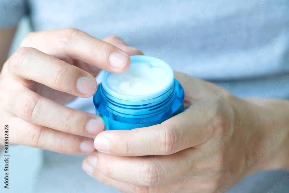 Hand of woman holding moisturizer cream and serum. She applying a facial cream , essential , oil , lotion and body cream for skin care, close up view and blur background. Beauty and Healthy Concept. Hand of woman holding moisturizer cream and serum. She applying a facial cream , essential , oil , lotion and body cream for skin care, close up view and blur background. Beauty and Healthy Concept.