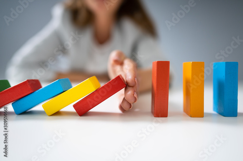 Businessperson Hand Stopping Colorful Blocks From Falling
