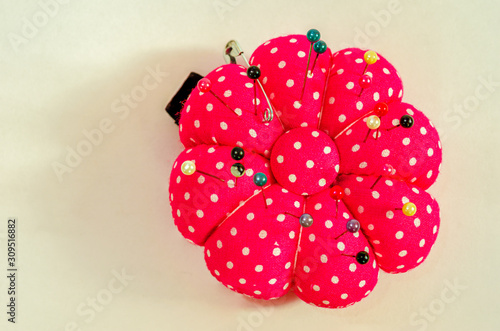 Above view of a red pin cushion with pins