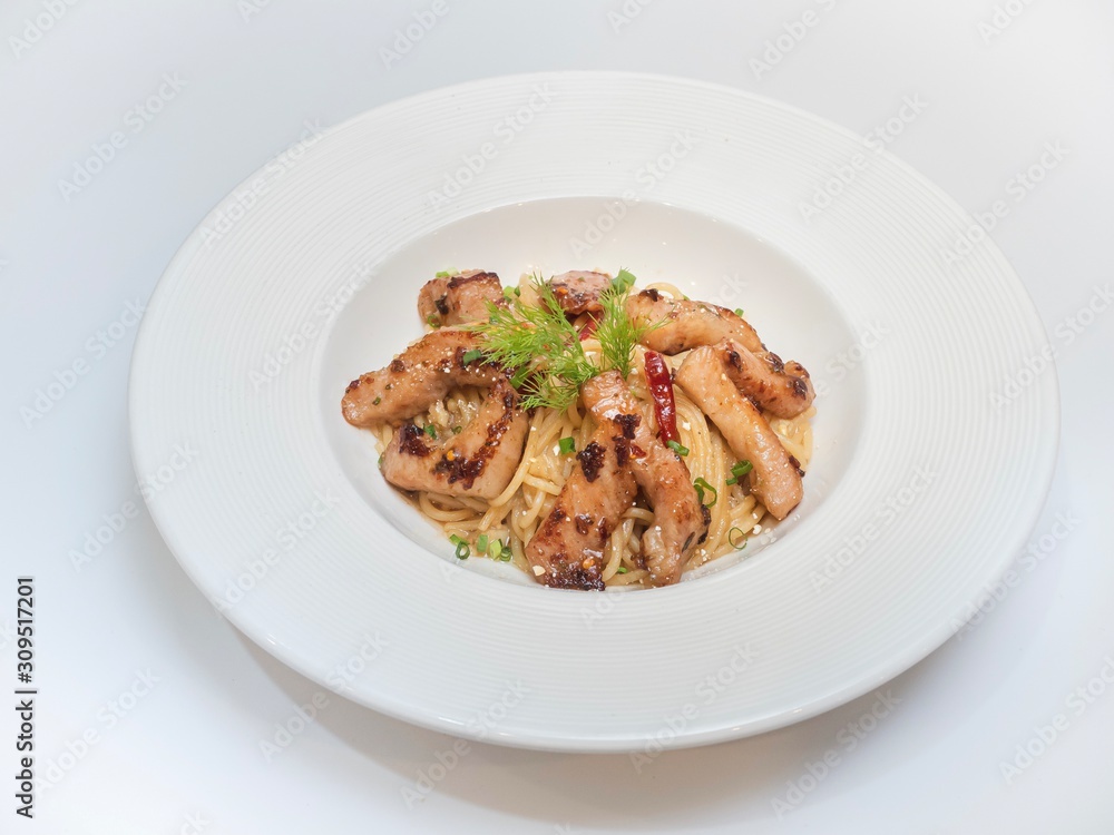 Charcoal-boiled pork neck spicy pasta, served in white dish garnished with dill leaves on white background, Fusion food Thai style image, Isolated image.
