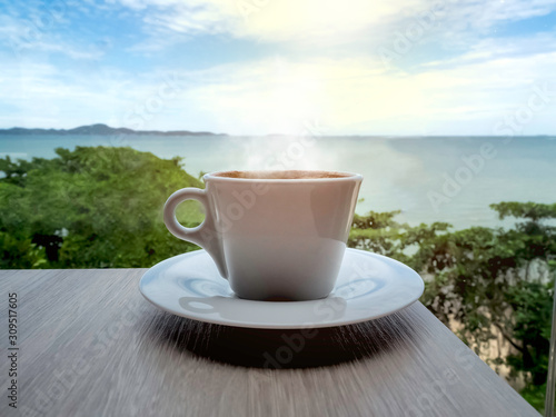 Close up a cup of black coffee on a wood table and sea-view background in the late morning of vacation time.