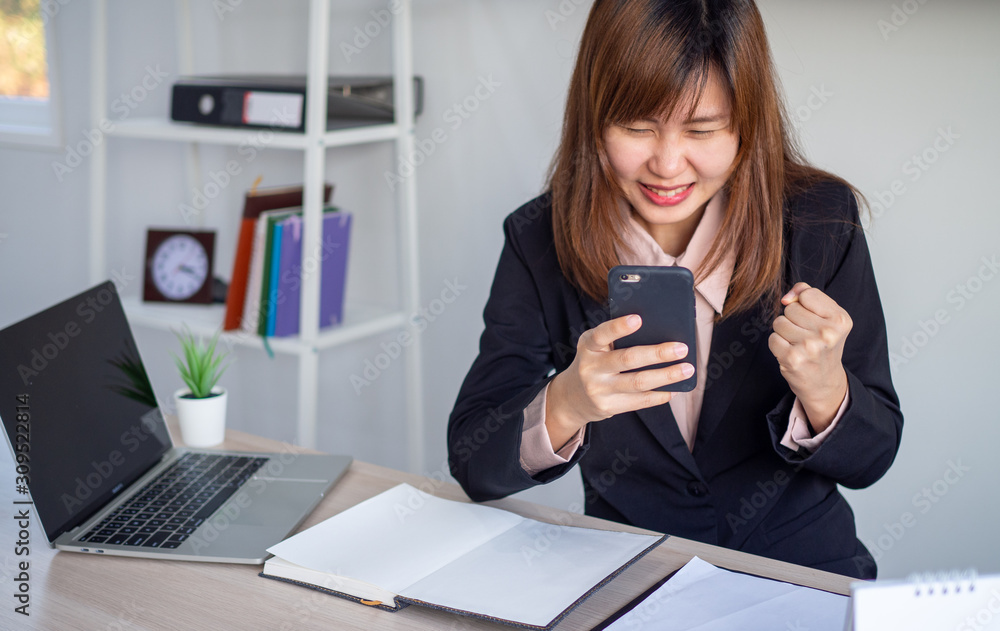 An Asian businesswoman looks happy while looking at the information on the phone. An Asian businesswoman looks happy while looking at the information on the phone.