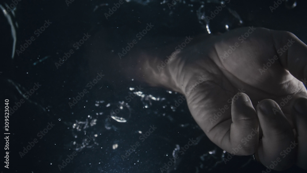 With the palm of your hand, check or mix the water. Bottom view from under the water. Divine god hand. A finger is wearing a ring. Black background. Around the air bubbles and flows. With the palm of your hand, check or mix the water. Bottom view from under the water. Divine god hand. A finger is wearing a ring. Black background. Around the air bubbles and flows.