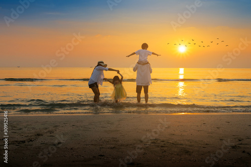 Cheerful family are dancing on the beach and sunset in the summer.