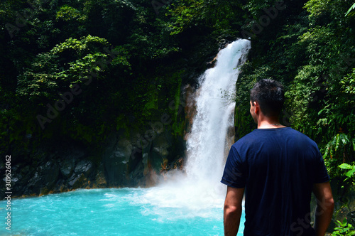 Guy hiker is watching tropical waterfall - Rio Celeste, Costa Rica